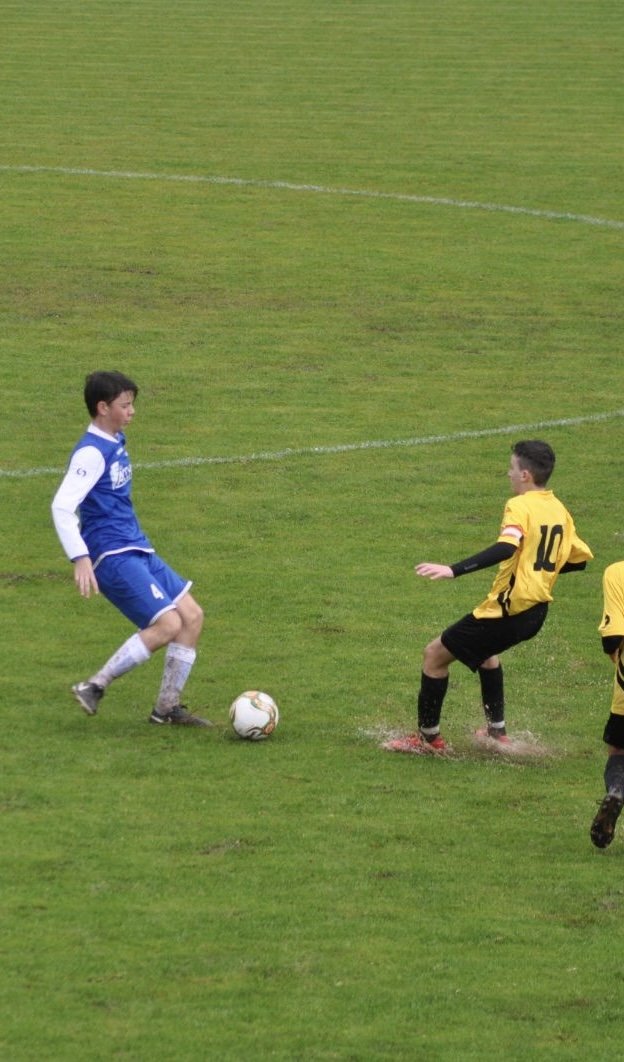 Matteo playing competitive football, number 4 in blue